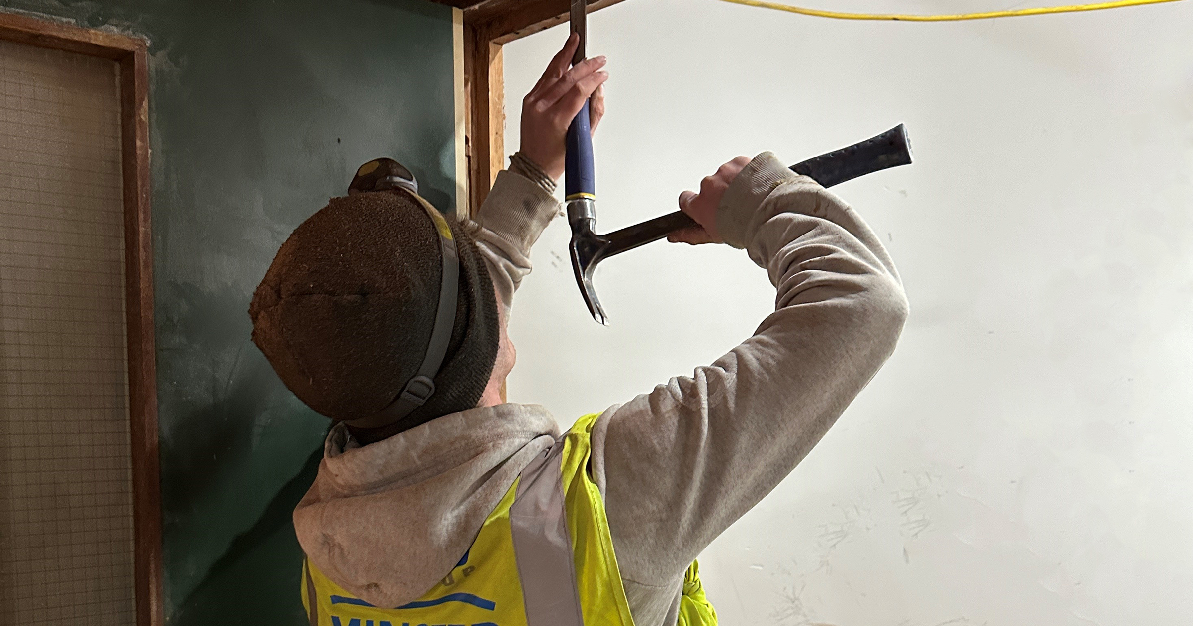 A member of the MJS Group team chisels a wooden door frame in Brook House at Winslade Park